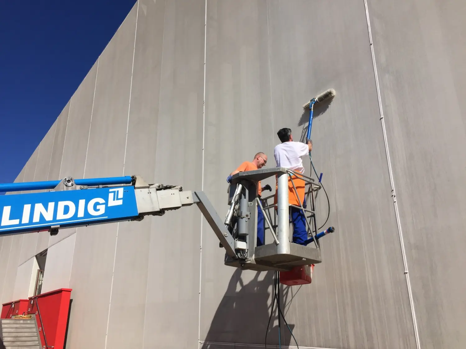 Moderne Raumpflege GmbH Boge - Gebäudereinigung - Arbeiter reinigen die Außenwand eines Gebäudes mit einem Lindig-Arbeitsbühnenlift oder einer Hubarbeitsbühne.
